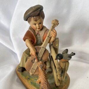 The Vintage Anri Hand Carved Boy Playing Fiddle is a small wooden sculpture